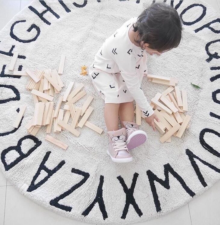 oung boy happily playing on a colorful, soft Valela play mat, designed for comfort and fun at home.