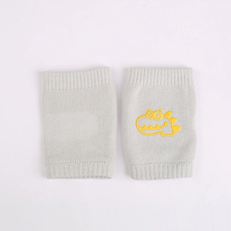 Gray knit baby leg warmers with a yellow alligator design on a white background