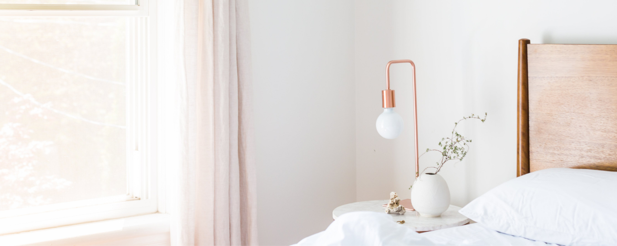 Modern bedroom with wooden bed, white bedding, and a small lamp on a nightstand.